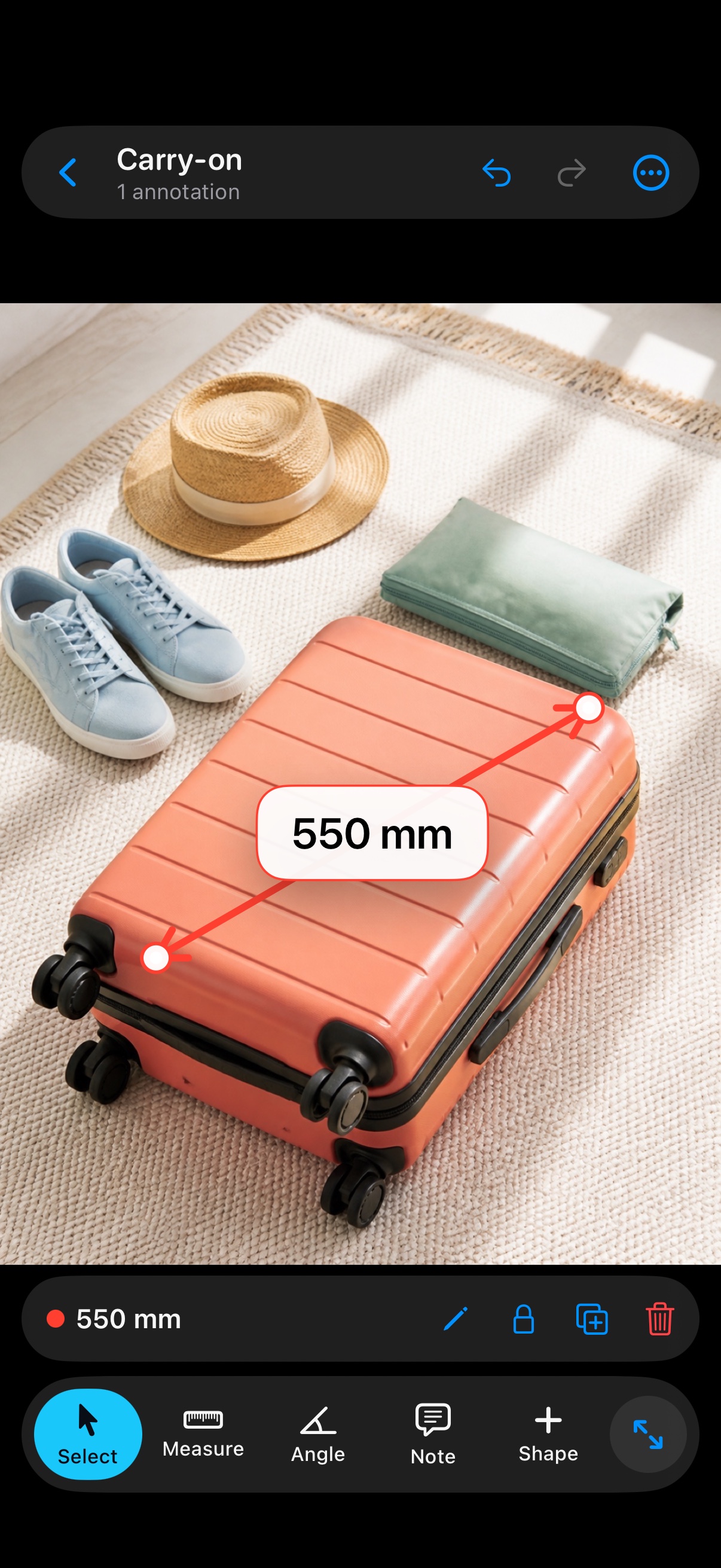 A 550 millimeter dimension marked across a bright coral carry-on suitcase